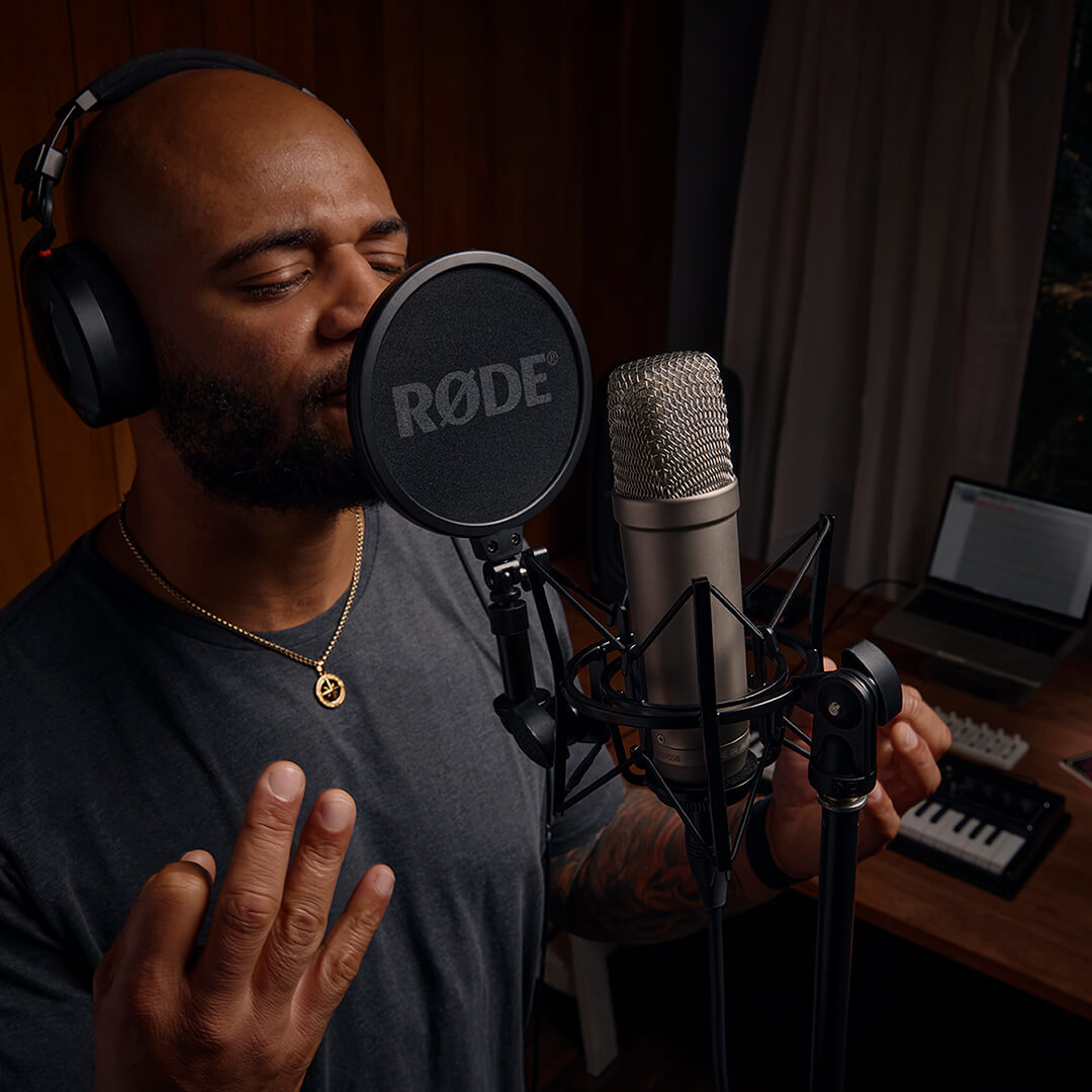 Man singing into NT1-A on SM6 with MIDI keyboard and computer in background